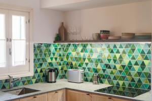 a kitchen with green and yellow tiles on the wall at Terra Nura in Son Xoriguer