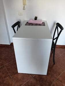 een witte tafel met twee stoelen en een roze kussen erop bij Seaside Deluxe Apartment in Durrës
