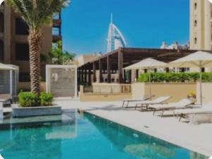 una piscina con mesas y sillas y un edificio en PENTHOUSE BURJ AL ARAB FRONT en Dubái
