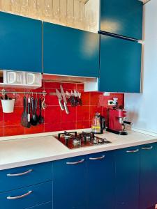 uma cozinha com armários azuis e uma parede vermelha em House with pool and private access to the sea 5* em Chiavari