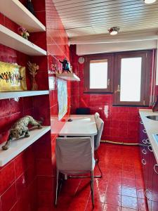 uma cozinha vermelha com uma mesa e um gato numa prateleira em House with pool and private access to the sea 5* em Chiavari
