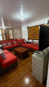 ein Wohnzimmer mit einem roten Sofa und einem TV in der Unterkunft Casa Hospedaje “YURAQ WASI” in Huaraz