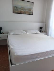 een wit bed in een slaapkamer met een foto aan de muur bij Seaside Deluxe Apartment in Durrës