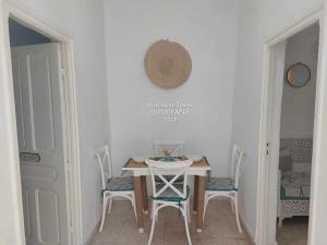 stół i krzesła w białym pokoju ze stołem i dwoma drzwiami w obiekcie Studio de charme w mieście Houmt Souk