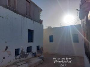 un edificio blanco con el sol brillando detrás de él en Studio de charme, en Houmt El Souk
