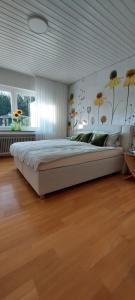 a large white bed in a bedroom with wood floors at Helle Ferienwohnung mit Garten und Terrasse, direkt am Waldrand gelegen in Herzogenrath