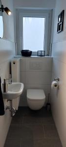 a bathroom with a toilet and a sink and a window at Helle Ferienwohnung mit Garten und Terrasse, direkt am Waldrand gelegen in Herzogenrath +9 photos