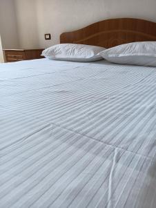 een wit bed met witte lakens en kussens bij Seaside Deluxe Apartment in Durrës