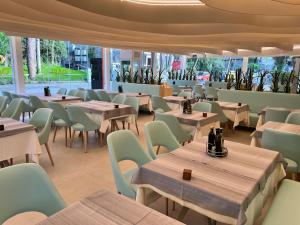 un restaurante con mesas y sillas de madera y ventanas en Hotel Oasi, en Lignano Sabbiadoro