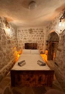 1 dormitorio con 1 cama en una habitación con paredes de piedra en Tarihi Mardin evi Hobbit ev en Mardin