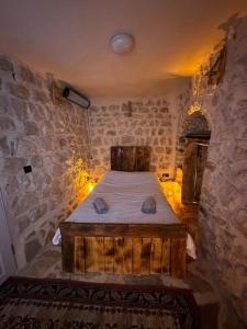 ein Schlafzimmer mit einem Bett in einer Steinmauer in der Unterkunft Tarihi Mardin evi Hobbit ev in Mardin