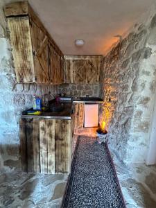 una cocina con armarios de madera y una pared de piedra. en Tarihi Mardin evi Hobbit ev en Mardin