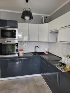a kitchen with white cabinets and a sink at Apartament DeLuxe 4 in Oświęcim