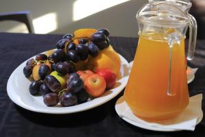 a plate of fruit and a pitcher of orange juice at Etang Hotels in Nata