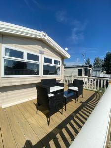 una terrazza con sedie e un tavolo su una casa di 8 Bed Sun Decked Caravan Unlimited High speed Wifi and fun at Seawick Holiday Park a Clacton-on-Sea