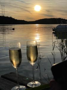 two glasses of wine sitting on a table near a lake at Charmig liten stuga i Södertälje/ Kungsdalen in Södertälje
