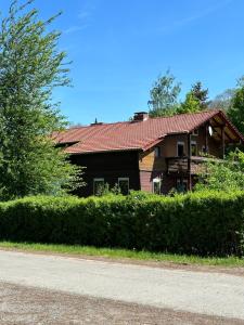ein Haus mit rotem Dach und einigen Büschen in der Unterkunft Erholungsoase im Vorharz in Katlenburg-Lindau
