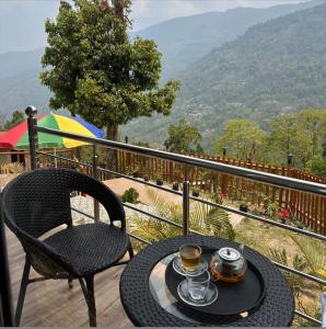 a table and a chair on a balcony with a drink at Majestic Zen Farmstay in Darjeeling
