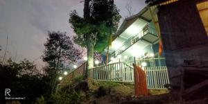una casa con un árbol delante de ella por la noche en Majestic Zen Farmstay, en Darjeeling