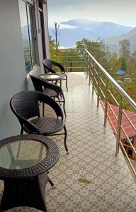 three chairs and tables on a balcony with a view at Majestic Zen Farmstay in Darjeeling
