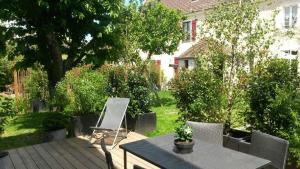 een patio met een tafel en stoelen in een tuin bij Les Co Gîte in Vigny