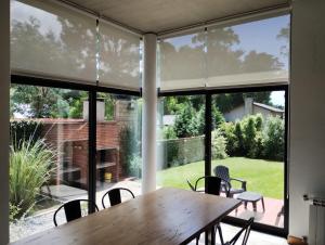 a dining room with a wooden table and large windows at Casa Huarpes MDP en Bosque Peralta Ramos in Mar del Plata
