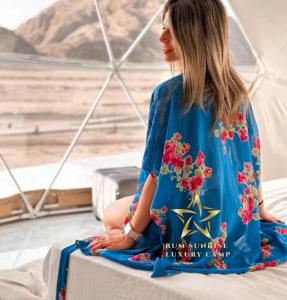 una mujer sentada en una cama mirando hacia el desierto en RUM SUNRlSE LUXURY CAMP en Wadi Rum