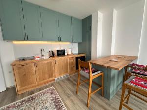 a kitchen with green cabinets and a wooden table at Empress N Apartment in Kosovo Polje +33 photos