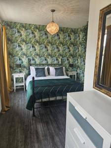 a bedroom with a bed with a green and blue wallpaper at No 2 The Terrace in Rainhull