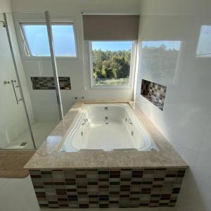 uma grande banheira na casa de banho com uma janela em Casa de campo espetacular condomínio a 50min de SP em Itupeva