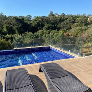 una piscina con 2 sillas en una terraza de madera en Casa de campo espetacular condomínio a 50min de SP en Itupeva