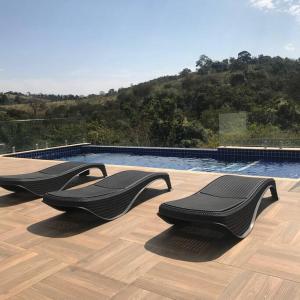 dos sillas negras sentadas en una terraza cerca de una piscina en Casa de campo espetacular condomínio a 50min de SP en Itupeva