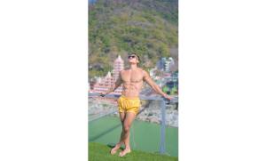 a shirtless man standing on top of a fence at Hotel Ishan - A Riverside Retreat by Salvus in Rishīkesh