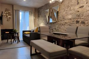 Una sala de estar con una mesa y una pared de piedra. en Loft Éfeso: ¡Un Refugio Moderno en Val'Quirico!, en Santeagueda