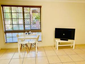 a living room with a white table and a tv at Granny flat in Brisbane
