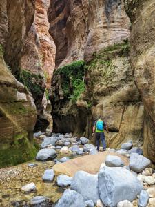 a man walking through a river in a canyon at Bedouin outdoors Camp wild in Dana