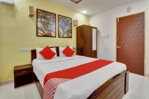 a bedroom with a large bed with red pillows at OYO Flagship Hotel Shiva Shakthi Inn in Bangalore