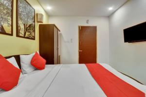 a bedroom with a bed with red pillows and a television at OYO Flagship Hotel Shiva Shakthi Inn in Bangalore