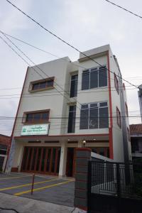 een wit gebouw met zwarte ramen op een straat bij Cipada Guesthouse syariah in Sumedang