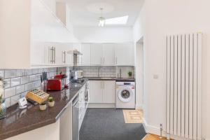 een keuken met witte kasten en een wasmachine en droger bij City Comforts Spacious 1BR with Furnished Kitchen in Londen