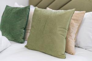 drie groene kussens bovenop een bed bij City Comforts Spacious 1BR with Furnished Kitchen in Londen