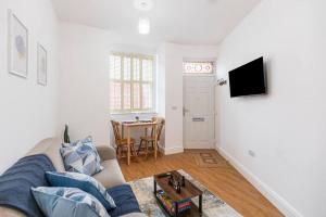 een woonkamer met een bank en een tafel bij City Comforts Spacious 1BR with Furnished Kitchen in Londen