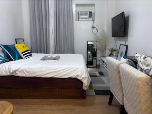 - une chambre avec un lit, une télévision et un canapé dans l'établissement Cozy Staycation for Families & Couples at Trees Residences Near SM Fairview Quezon City, à Quezon City
