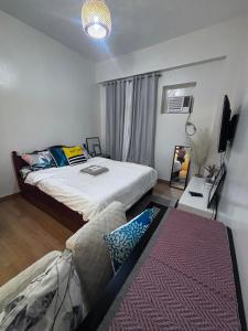 - une chambre avec un lit, un canapé et une télévision dans l'établissement Cozy Staycation for Families & Couples at Trees Residences Near SM Fairview Quezon City, à Quezon City