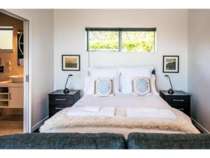 a bedroom with a large bed and a window at Delamore Cove - Manuka - Waiheke Escapes in Matiatia Bay
