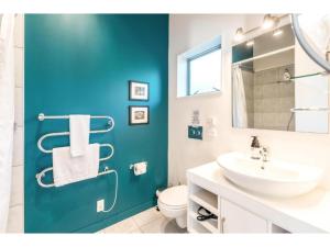 a bathroom with a white sink and a blue wall at Delamore Cove - Manuka - Waiheke Escapes in Matiatia Bay