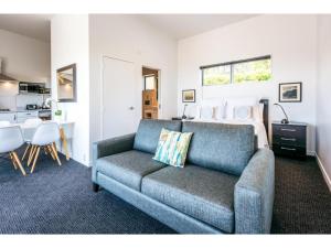 a living room with a couch and a bed at Delamore Cove - Manuka - Waiheke Escapes in Matiatia Bay