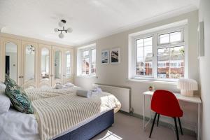 1 dormitorio con 1 cama y escritorio con silla roja en Seaview Symphony Opulent 4BR Haven for Big Groups, en Birchington