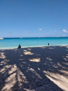 two people sitting on a beach looking at the ocean at Boracay Luxury Apartments in Boracay