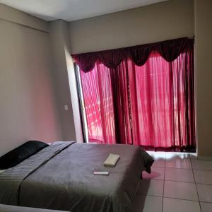 1 dormitorio con 1 cama y una ventana con cortinas rojas en Restaurante y Hostal Romayor en El Congo